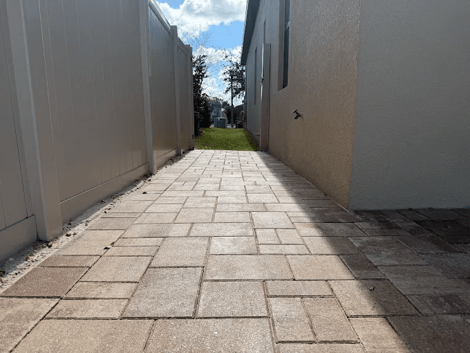 A clean brick paver walkway running along the side of a house