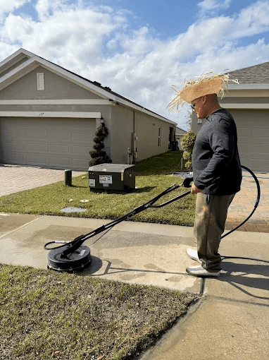 Angel, owner of El Coqui Pressure Washing & Sealing, cleaning a driveway with a surface cleaner